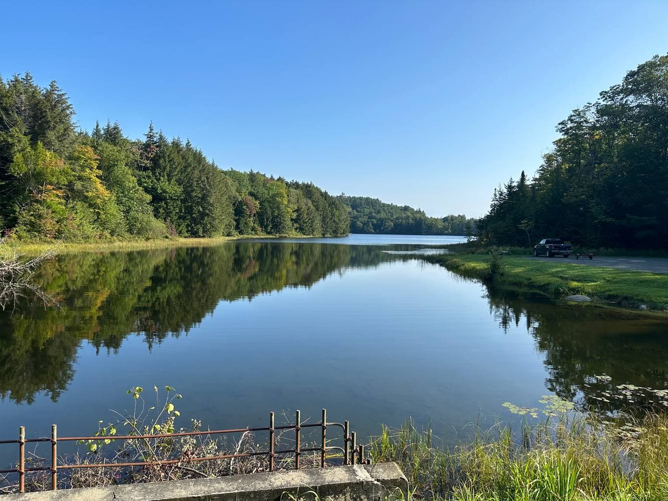 Miller Pond itself under a deep blue September sky, evergreens mirrored in the glassy water